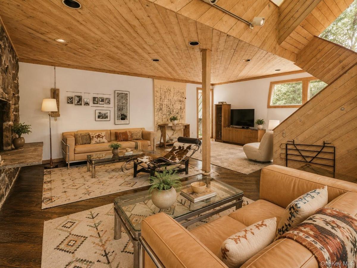Spacious Living room with cathedral ceilings, floor to ceiling windows, sliding glass doors and a beautiful stone fireplace