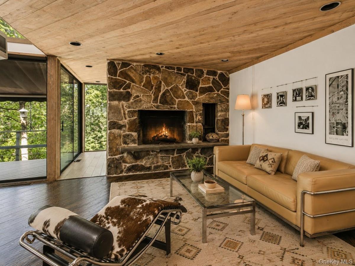 Spacious Living room with cathedral ceilings, floor to ceiling windows, sliding glass doors and a beautiful stone fireplace
