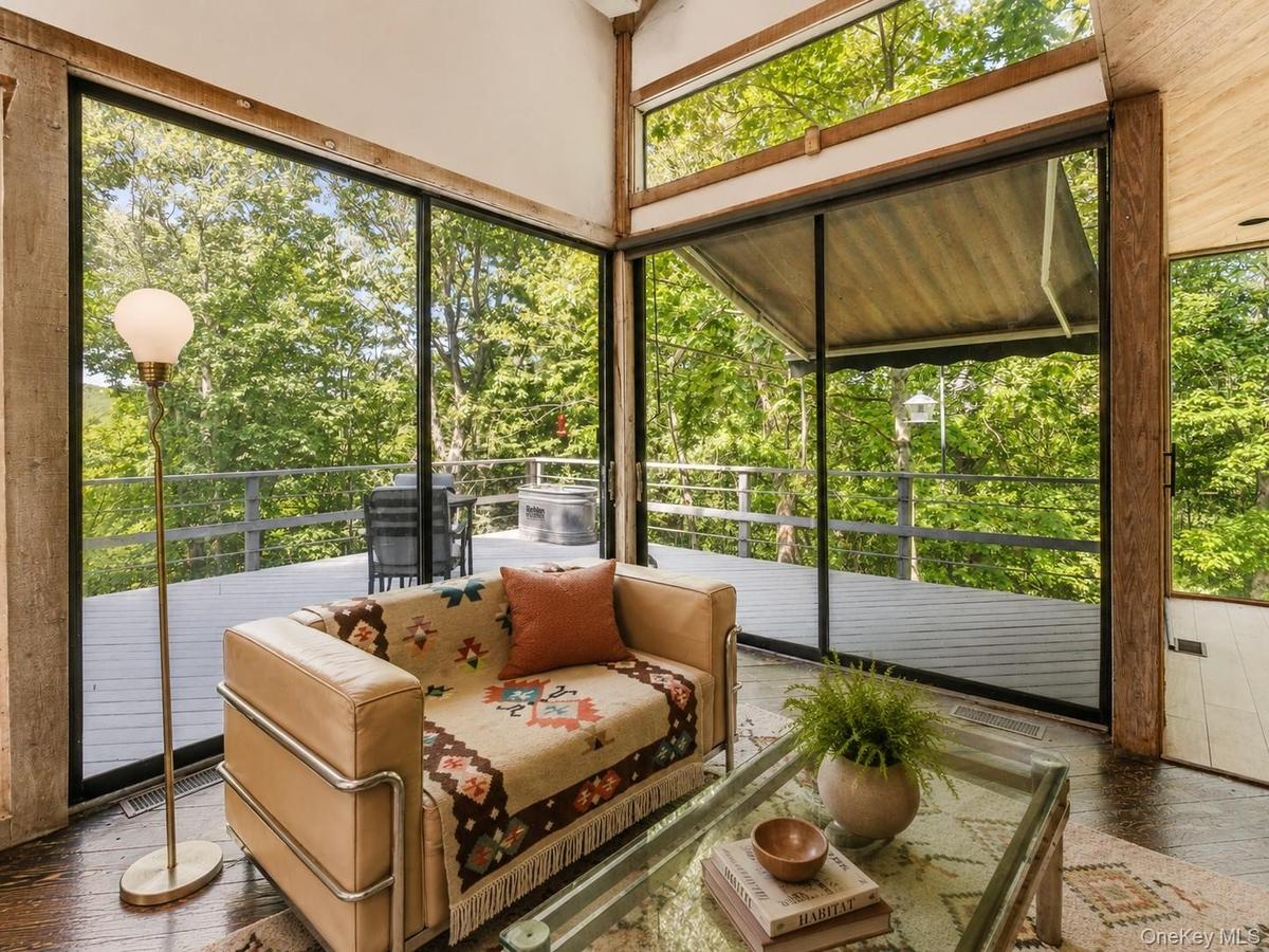 Spacious Living room with cathedral ceilings, floor to ceiling windows, sliding glass doors and a beautiful stone fireplace