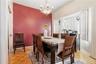 Dining area featuring a prominent red accent wall, parquet wood-finish flooring, and an elegant chandelier
