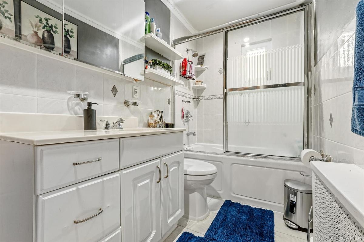 Bathroom with a white vanity featuring a light-toned countertop and chrome hardware