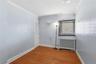 Second floor Bedroom 2 featuring wood-finish flooring, light blue paneled walls, white trim, a louvered bi-fold door, and a window with horizontal bli