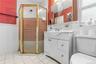Bathroom featuring an enclosed corner shower with a gold-finish frame, a white vanity with integrated sink, a mirrored medicine cabinet, a window, and