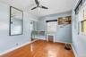 Room featuring wood-finish flooring, a ceiling fan, sliding mirror closet doors, and multiple windows with blinds