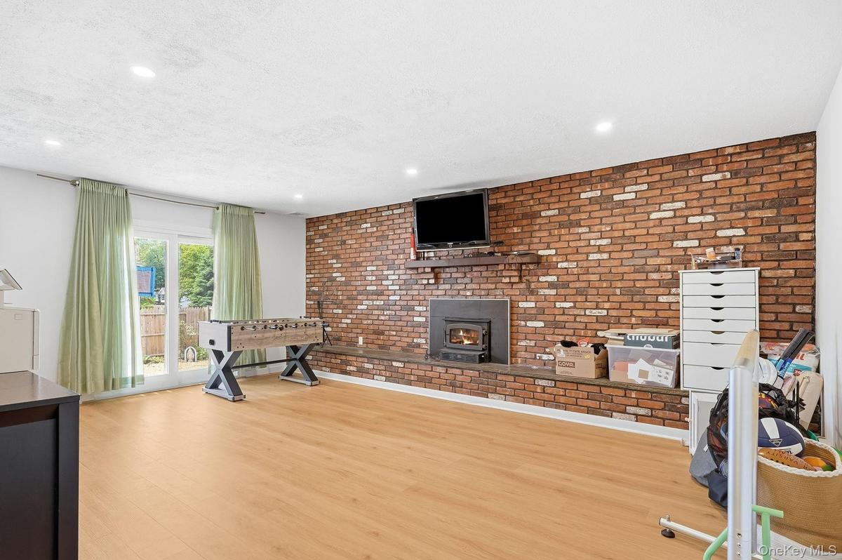 Lower-Level Family Room with Exposed Brick, Fireplace and Sliders to Rear Yard