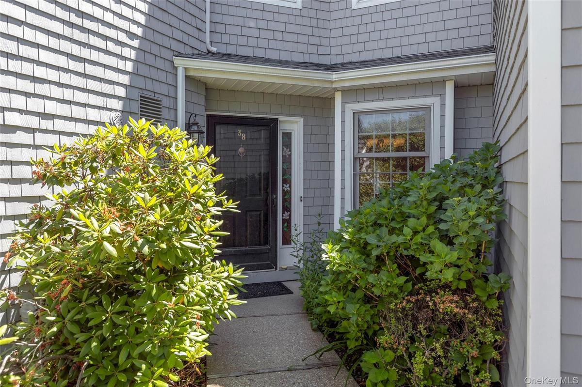 Entryway featuring a dark paneled door with a storm door, an overhead light fixture, and a single-pane window with white trim