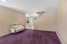 Spacious room with plush carpeting and neutral tone walls, featuring a staircase to second level