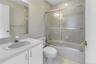 Bathroom featuring a white vanity with integrated sink, chrome faucet, and expansive wall mirror