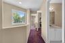 Hallway featuring a large window with grid pattern, neutral wall tones, recessed lighting, and burgundy carpeting