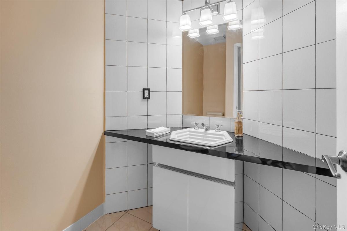 Bathroom vanity with a black countertop, white under-sink cabinetry, and a rectangular mirror