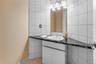 Bathroom vanity with a black countertop, white under-sink cabinetry, and a rectangular mirror