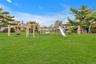 Expansive green space featuring a large playset with slides, swings, and climbing structures