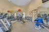 Dedicated fitness center featuring multiple weight machines, cardio equipment, mirrored walls, and a light-colored carpeted floor