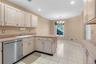 Kitchen featuring white cabinetry, light countertops, a stainless steel dishwasher, and white tile flooring