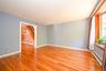 Spacious room with Pre-engineered hardwood flooring, light blue wall paint, and a large bay window with wood trim.