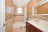 Full bathroom featuring a single vanity with a solid surface countertop, medicine cabinet, tiled bathtub surround with a mosaic accent band, and tiled