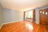 Spacious room with Pre-engineered hardwood flooring, light blue wall paint, and a large bay window with wood trim.