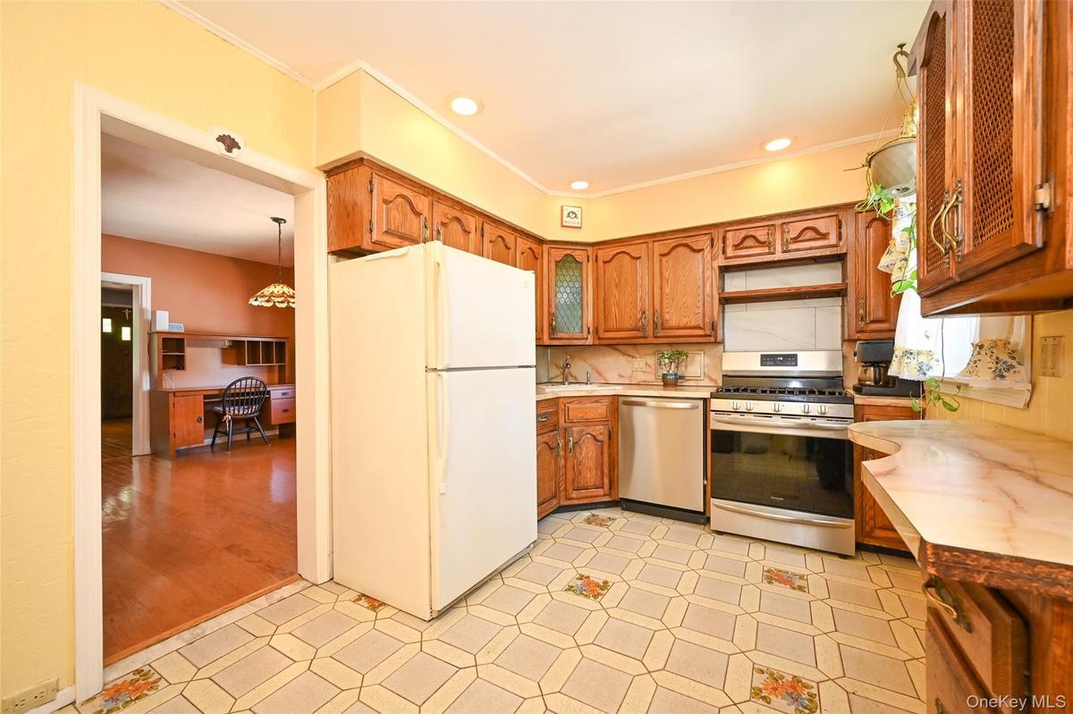 Kitchen featuring wood cabinetry, stainless steel range and dishwasher, patterned floor tiling.