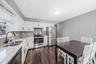 Kitchen featuring white cabinetry, gray subway tile backsplash, light-toned stone-finish countertops, stainless steel appliances, and dark wood-finish