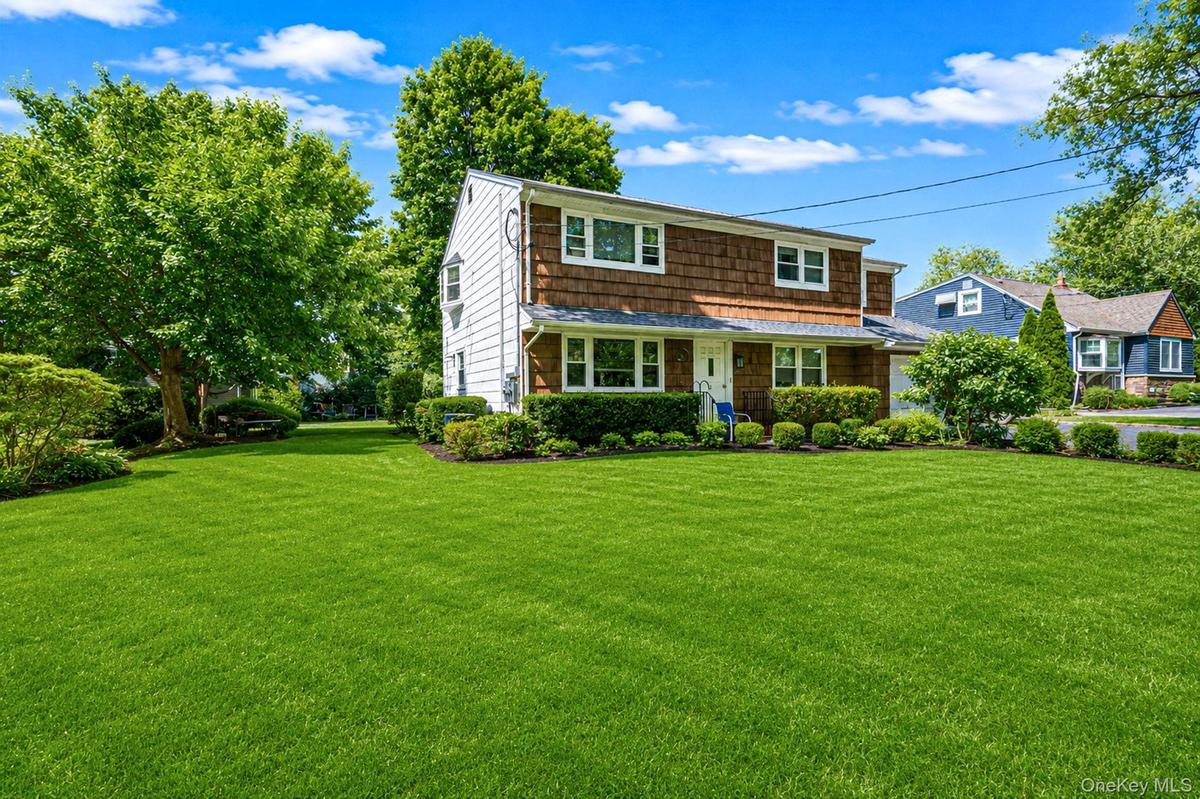 Two-story residence featuring a shingled upper facade and white siding on the lower level