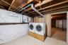 Laundry area featuring exposed wood joists, utility piping, and a white framed window