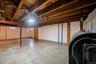 Spacious unfinished basement featuring exposed wood ceiling joists, concrete flooring, and perimeter wall insulation