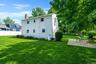 Expansive backyard featuring a lush lawn, mature trees, and a paver patio