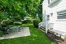 Expansive backyard featuring a lush lawn, mature trees, and a concrete patio