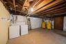Basement utility space featuring exposed wood joists, a washer and dryer, two yellow water heaters, and a small window