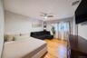 Bedroom featuring wood-finish flooring, a ceiling fan with integrated lighting, window with light-filtering drapes, and built-in shelving
