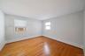 Interior space featuring wood-finish flooring, two window openings, and baseboard heating elements