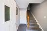 Entryway featuring a decorative glass-paneled door, textured carpeting, a white paneled door, and a staircase with wood-finish handrail and carpeted t