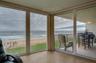 Expansive glass doors open directly to the covered balcony, creating seamless indoor-outdoor flow and capturing stunning views of the sand and surf.