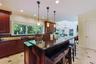 Kitchen featuring a large island with seating, pendant lighting, dark wood cabinetry, a tile backsplash, and recessed lighting