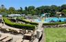Community aquatic area featuring a large swimming pool, a separate shallow play pool with water features, and surrounding concrete lounge decks