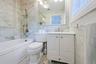Bathroom featuring a white vanity with a single basin, a chrome faucet, and a large wall mirror with integrated lighting