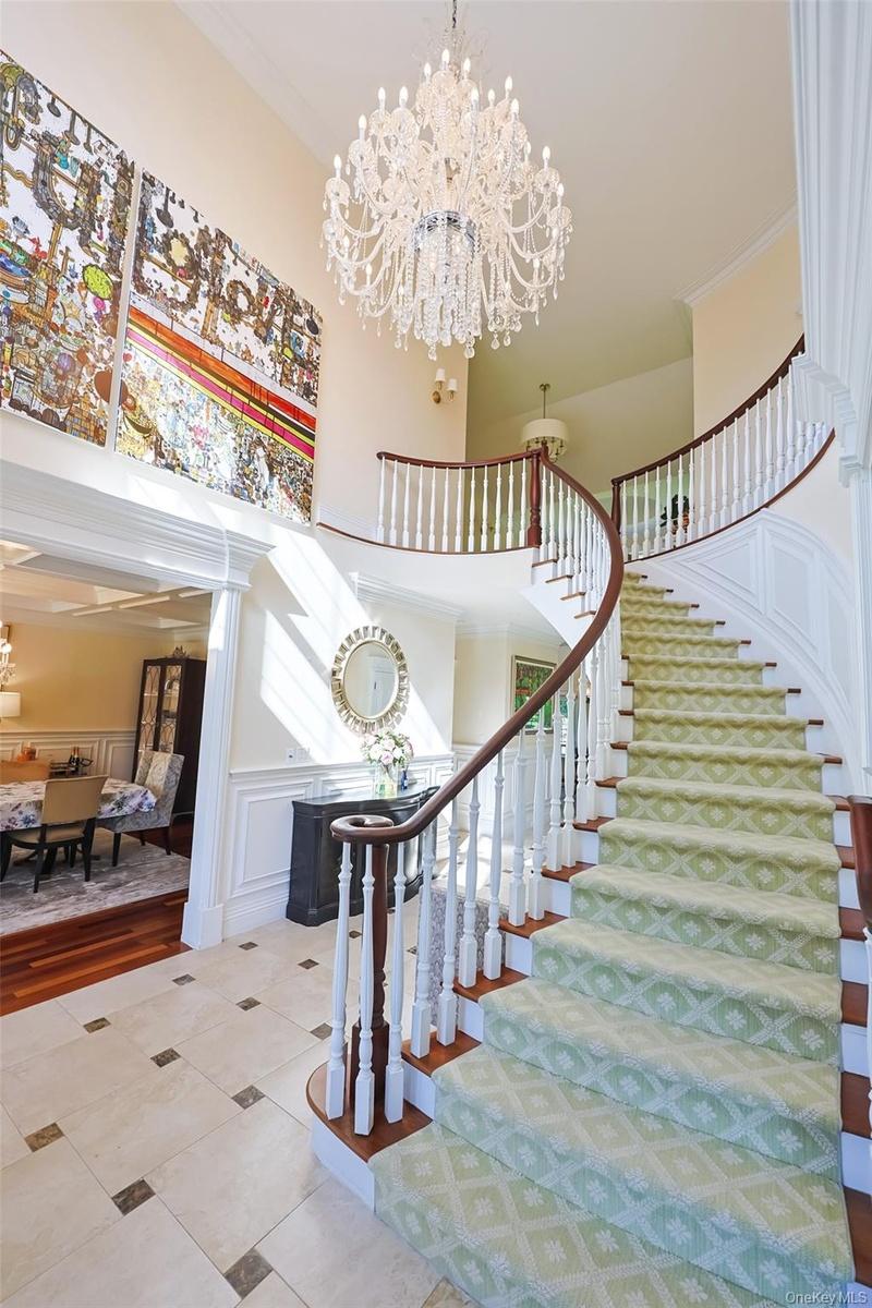 Grand foyer featuring a curved staircase with a dark wood handrail and white spindles