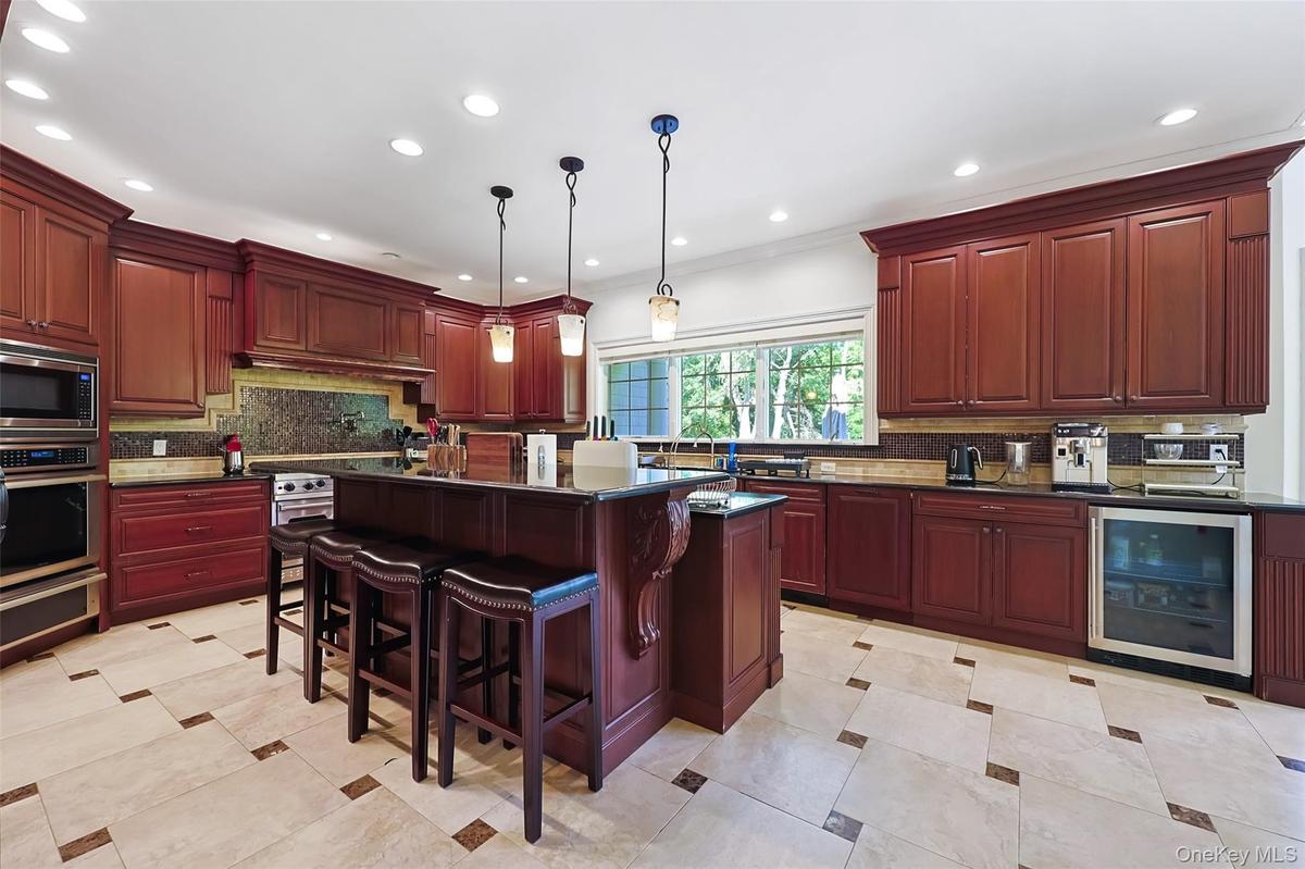 Kitchen featuring cherry wood cabinetry, recessed lighting, a central island with pendant lights, integrated stainless steel appliances, and tile floo