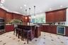 Kitchen featuring cherry wood cabinetry, recessed lighting, a central island with pendant lights, integrated stainless steel appliances, and tile floo