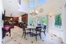 Open-concept kitchen and dining area featuring high ceilings, large windows, tile flooring with decorative inserts, and rich wood cabinetry