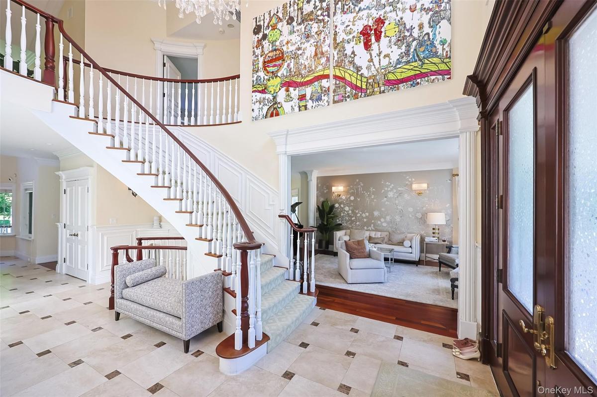 Grand foyer featuring a curved staircase with rich wood handrails and white balusters