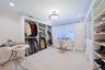 Spacious dressing room featuring extensive custom built-in cabinetry, recessed lighting, and a large window with blinds