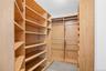 Custom closet system featuring light wood-finish shelving, multiple hanging rods, and integrated shoe storage and dimmable overhead lighting