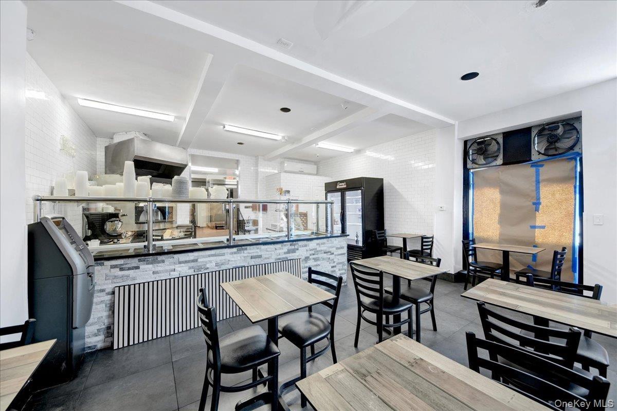 Commercial space featuring dark tile flooring, white subway tile walls, a service counter with stacked stone and vertical paneling, and an integrated 