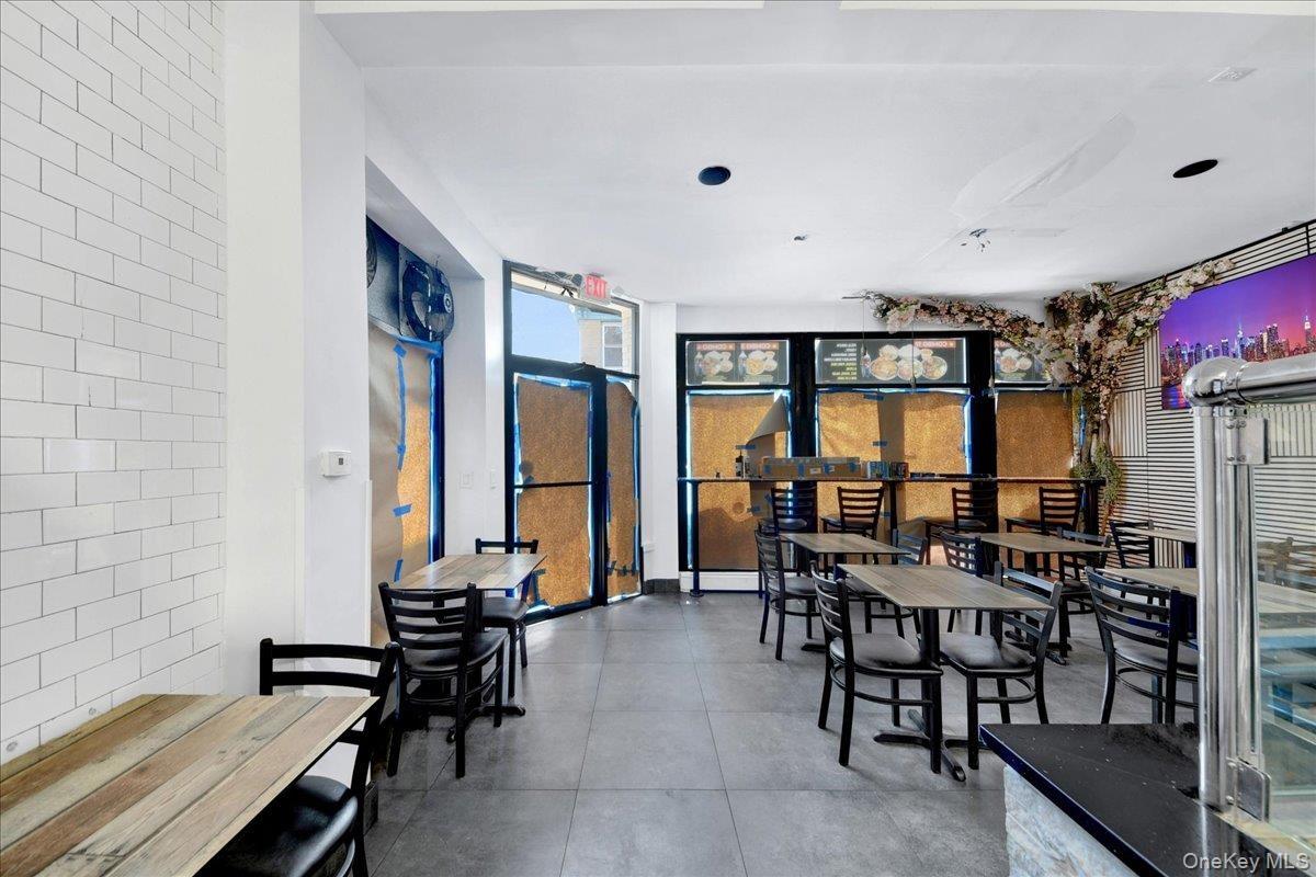 Spacious commercial interior featuring white subway tile accent wall and dark gray floor tiling