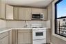 Top Floor Apartment Kitchen featuring taupe shaker-style cabinetry, white subway tile backsplash, light-toned countertops, and a stainless steel micro