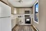 Full kitchen featuring white appliances, stainless steel microwave and range, light-toned cabinetry, and wood-finish flooring