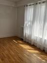 Room featuring wood-finish flooring, white baseboards, and a large window with sheers