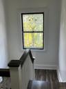 Staircase landing featuring a decorative stained glass window, dark wood-finish flooring, white painted walls, and a white and dark-stained wood balus