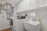 Indoor laundry room with new washer/dryer, upper storage cabinets, wash tub and closet.  Full electrical upgrade in 2024 with new panel, copper feeds 